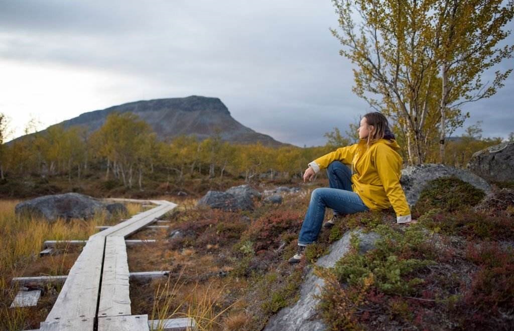 Finland, Lappland, Kilpisjaervi, woman sitting at wooden boardwalk - Places to Visit in Finland - Planet Travel Advisor Finland, Lappland, Kilpisjaervi, woman sitting at wooden boardwalk - Places to Visit in Finland - Planet Travel Advisor