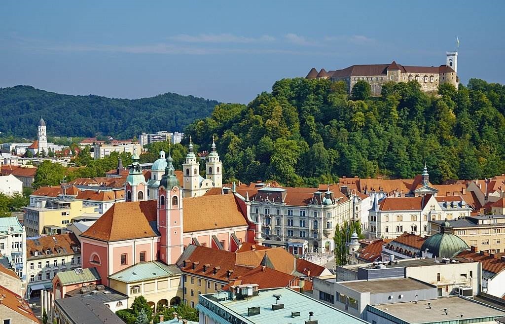 Slovenia, Ljubljana, cityscape with Franciscan church, Saint Nicholas church and the Castle - Best Time to Visit Europe - Planet Travel Advisor