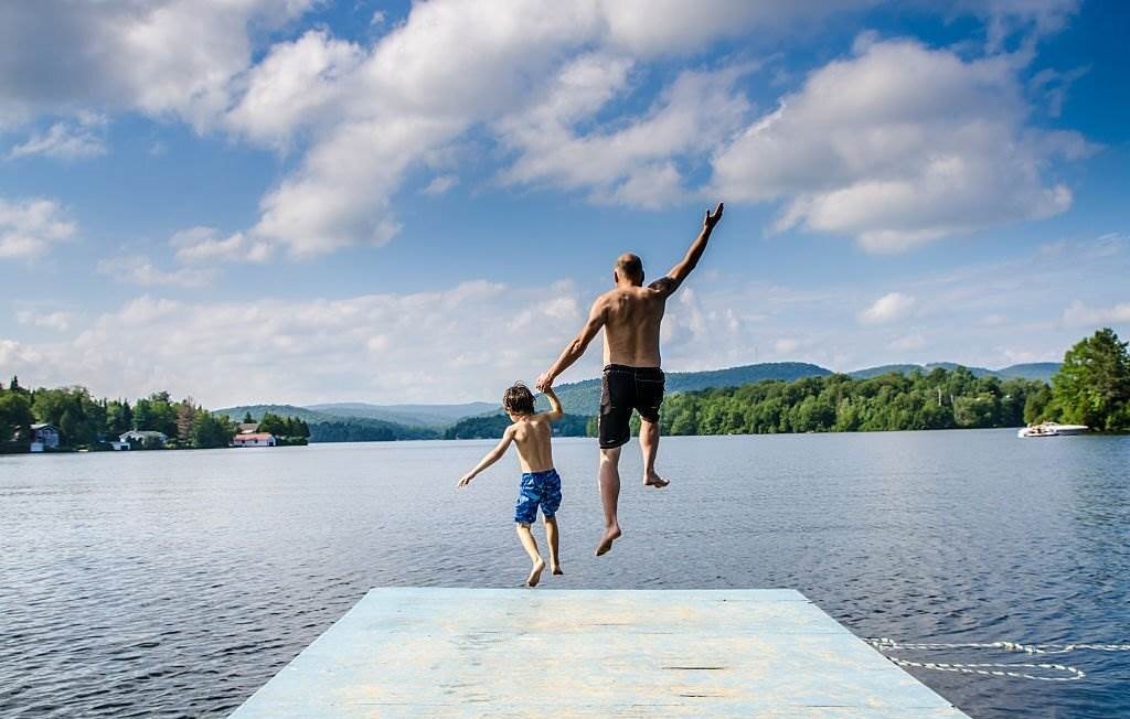 Father and Son Jumping in Lake Sept-Iles in Canada (Portneuf) from the dock - Canada During Summer - Best Time to Visit Canada - Planet Travel Advisor