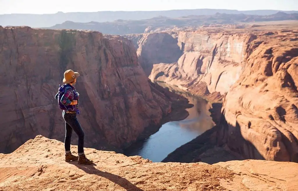 The Grand Canyon National Park - A Woman Hiking on the Edge of a Senic Overlook - Natural Attractions in USA - Planet Travel Advisor